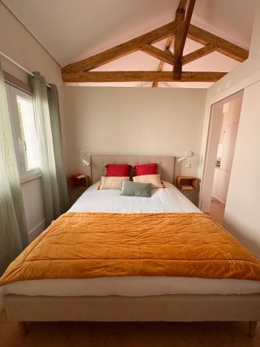 a bedroom with a large bed with orange blanket at Lezíria Houses - Ribatejo in Chamusca