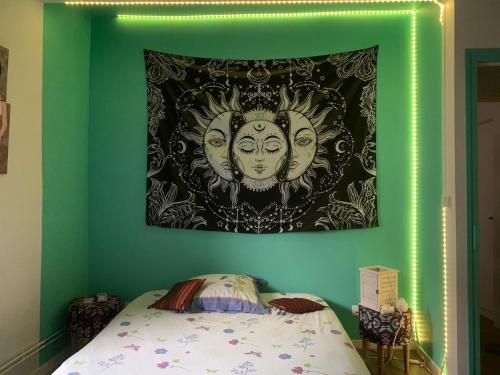 a painting of two faces on a wall above a bed at MAISON DE VILLE à Saint-Junien in Saint-Junien