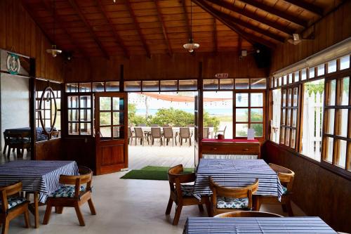 a restaurant with two tables and chairs and windows at Hotel Albemarle Galapagos Beachfront in Puerto Villamil