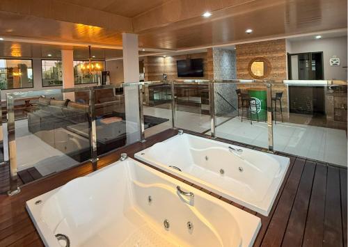 a bath tub in a bathroom with glass walls at Luxo Frente Mar em 7 Qtos com Ar sendo 4 suites para até 18 pessoas, 2 Jacuzzi Aquecidas, piscina, brinquedoteca, 5min de Castelhanos in Anchieta