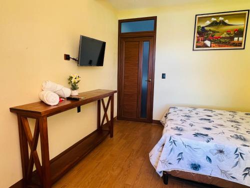 a bedroom with a bed and a desk with a television at Alojamiento el Abuelo in San Pedro La Laguna