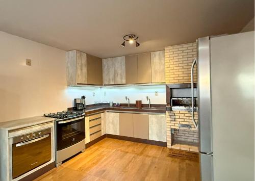 a kitchen with stainless steel appliances and wooden floors at Luxo Frente Mar em 7 Qtos com Ar sendo 4 suites para até 18 pessoas, 2 Jacuzzi Aquecidas, piscina, brinquedoteca, 5min de Castelhanos in Anchieta