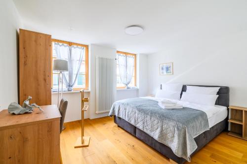 a bedroom with a bed and a desk and windows at Casa Rheinblick - Apartment C in Basel