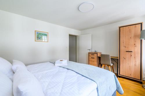 een witte slaapkamer met een bed en een bureau bij Casa Rheinblick - Apartment C in Bazel