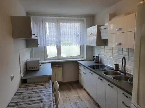 a kitchen with white cabinets and a sink and a window at Hostel Berberysowa in Wrocław