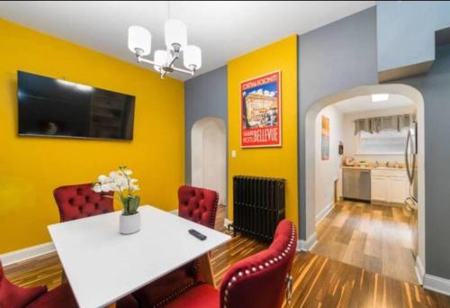 a dining room with yellow walls and a white table and chairs at Chic 5 BD home in Little Italy in Baltimore