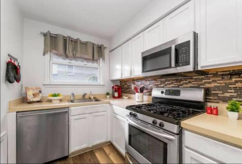 a kitchen with white cabinets and a stove top oven at Chic 5 Bd Home In Little Italy in Baltimore