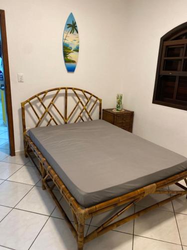 ein Bett in einem Zimmer mit einem Surfbrett an der Wand in der Unterkunft Casa térrea em Caraguatatuba in Caraguatatuba
