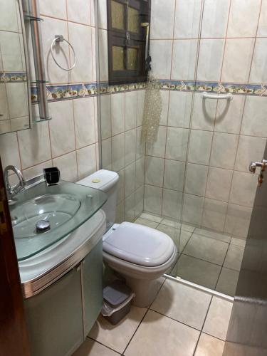 ein Badezimmer mit Toilette, Waschbecken und Dusche in der Unterkunft Casa térrea em Caraguatatuba in Caraguatatuba
