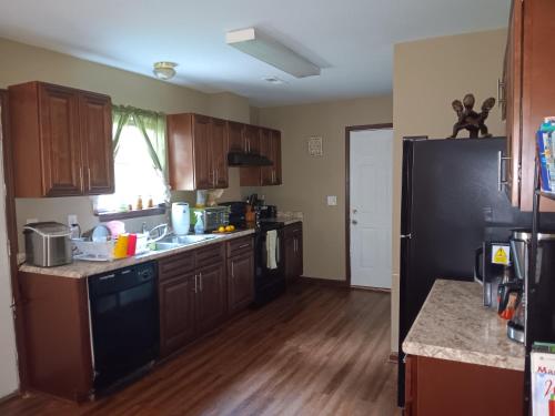 a kitchen with wooden cabinets and a black refrigerator at Be Our Guest in Charlotte