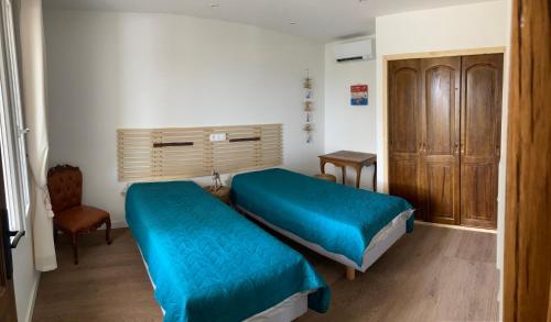 Una pequeña habitación con dos camas y una silla. en villa bormes les mimosas, en Bormes-les-Mimosas