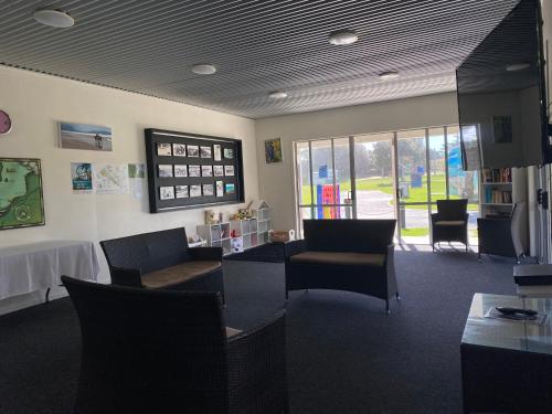a waiting room with chairs and a table in a library at Camp Waipu Cove in Waipu