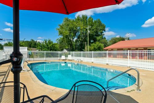 a swimming pool with a red umbrella next to it at Americas Best Value Inn and Suites Siloam Springs in Siloam Springs