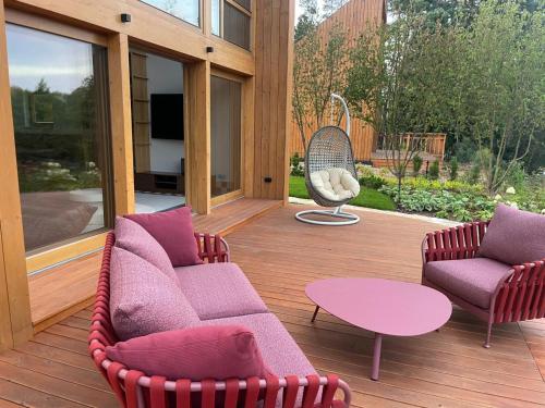 a patio with two chairs and a table on a deck at Kalbornia LAKE & POOL HOUSE by JWPM in Brzeźno Mazurskie