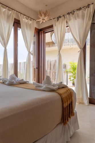 a bedroom with a bed with white curtains and a window at H Boutique Casa Noma-Noma Holbox in Holbox Island