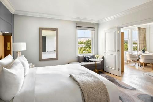 a bedroom with a large white bed and a living room at The Ritz-Carlton, Half Moon Bay in Half Moon Bay