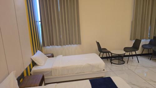 a hospital room with two beds and a table and chairs at Premvakita restaurant and hotel in Ratlām