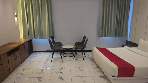 a hotel room with a bed and chairs and a table at Premvakita restaurant and hotel in Ratlām