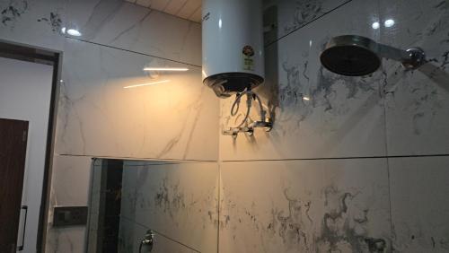 a bathroom with a light on the wall and a mirror at Premvakita restaurant and hotel in Ratlām