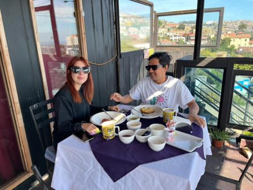 a man and a woman sitting at a table at Apart Hotel Jagui Haus Departamentos tipo Loft y Hermosa Terraza con vista al Mar in Valparaíso