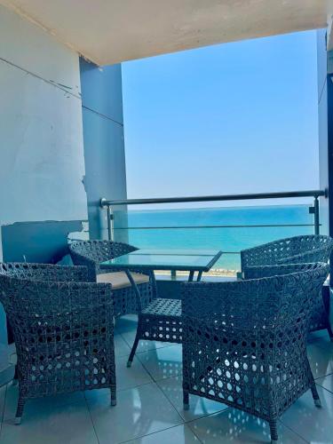 a table and chairs with a view of the ocean at ALEX HOMES - Gleem Luxury Apartments with Direct Sea View in Alexandria