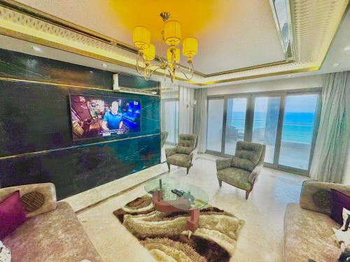 a living room with a tv and a table and chairs at ALEX HOMES - Gleem Luxury Apartments with Direct Sea View in Alexandria