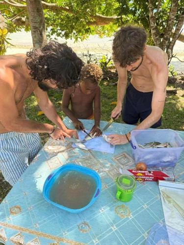 a group of three men standing around a table at Lonnoc ocean view beach bungalows in Hog Harbour