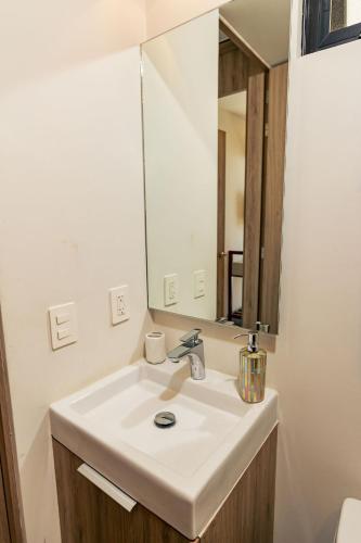 a bathroom with a white sink and a mirror at Apartment A/C, GYM, Cafeteria | Telmex Auditorium in Guadalajara