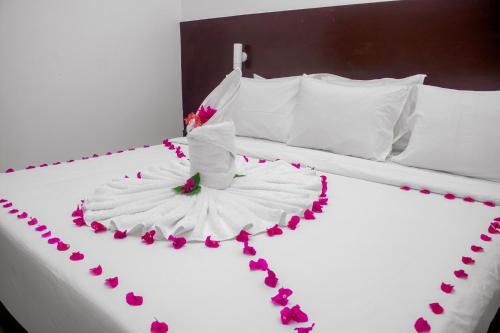 a bed with a white dress with pink flowers on it at Malika Nungwi Hotel in Nungwi