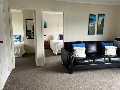 a living room with a black leather couch and a bed at Tipi and Bobs Waterfront Lodge in Tryphena