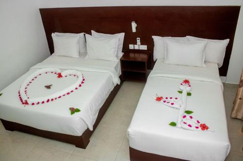 a hotel room with two beds with heart decorations on them at Malika Nungwi Hotel in Nungwi