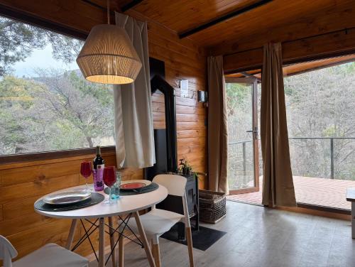 Un comedor con una mesa y un gran ventanal. en RIO-ABAJO Cabañas frente al RIO MELIQUINA, en Villa Meliquina