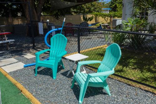 two blue chairs and a table in a yard at Casa Lula Beach Retreat - Fenced backyard in Arecibo