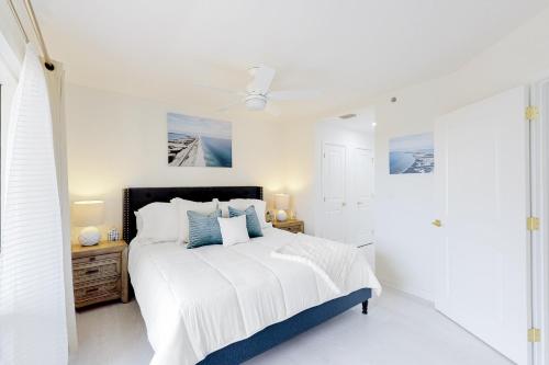 a white bedroom with a bed and a ceiling fan at Luau II 6229 in Destin
