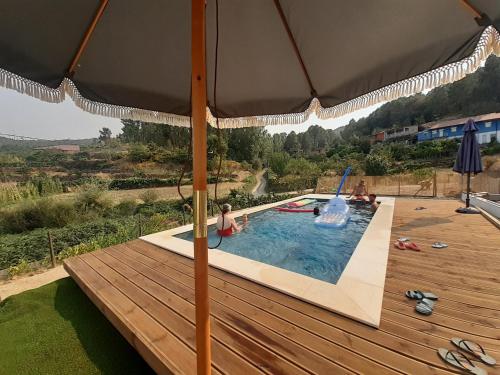 una piscina con terrazza in legno e ombrellone di Quinta da Peça Douro Wine Region Retreat, Private Pool Villa a Vila Real