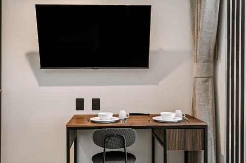 a table with a chair and a television on a wall at Suites Álamos by Homirent in Laborcillas