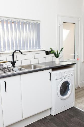 a white kitchen with a sink and a washing machine at Lohia Nights in Middlesbrough
