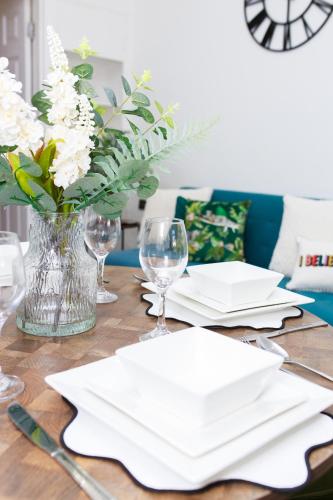 a wooden table with white napkins and a vase of flowers at Lohia Nights in Middlesbrough