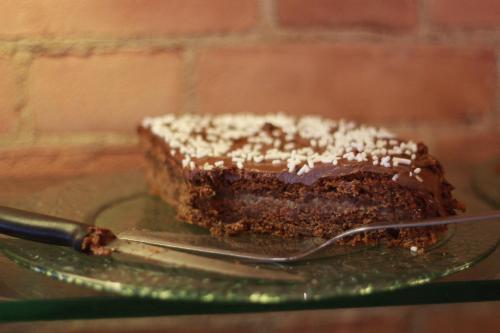 a piece of chocolate cake on a glass plate with a fork at Hotel Portici in Vicoforte