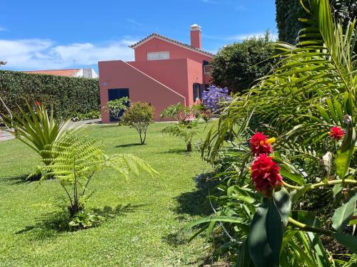 a garden with a pink house in the background at Garden Loft in Ribeira Grande