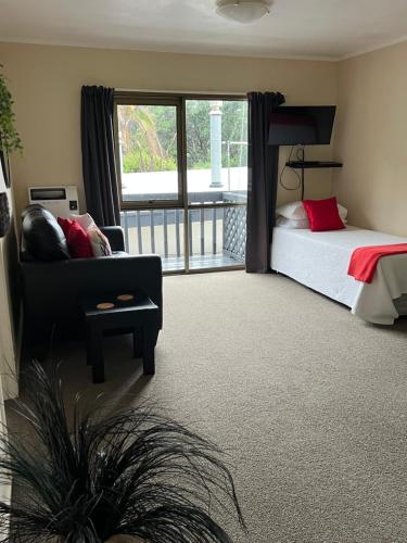 a bedroom with a bed and a couch and a window at Tipi and Bobs Waterfront Lodge in Tryphena