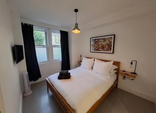 a bedroom with a bed with white sheets and a window at Elegant Garden Flat - Raynes Park in Raynes Park