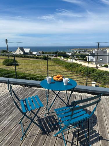 a table and chairs on a deck with a view of the ocean at GWEL KAER - Maison tout confort petite vue mer in Plouarzel