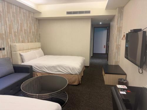 a room with two beds and a tv and a couch at Fairy Tale City Motel in Hualien City
