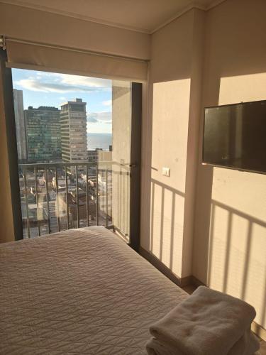 a bedroom with a balcony with a bed and a large window at Departamento Central Vip in Antofagasta