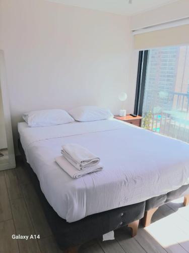 a white bed with two towels on top of it at Departamento Central Vip in Antofagasta