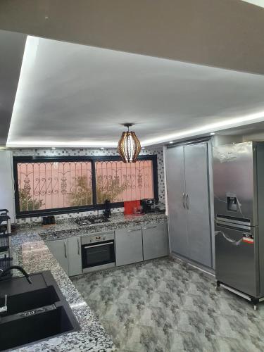 una cucina con mobili bianchi e una grande finestra di Villa entière a Azemmour