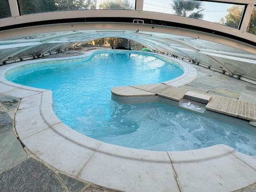 una piscina in un edificio con acqua blu di LES MAISONS DE GIROUDET 2 chambres terrasse et piscine a Écrosnes