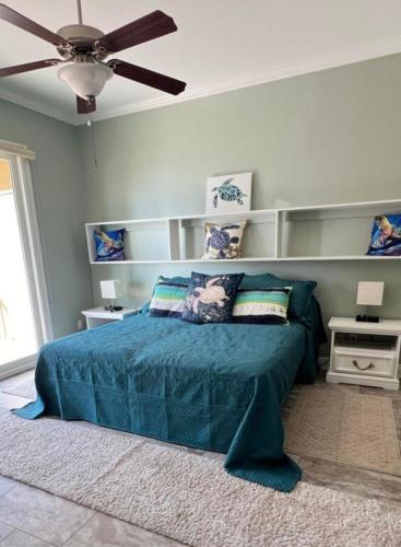 a bedroom with a blue bed and a ceiling fan at Beachside 1st Floor Condo in Pass Christian