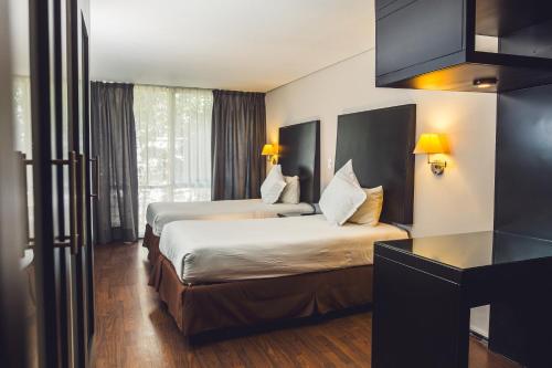 a hotel room with two beds and a desk at Suites Parioli in Mexico City